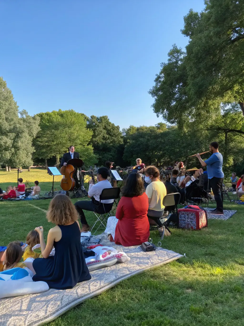 A documentary-style photo of a small ensemble performing outdoors in a public square, with an engaged audience of diverse backgrounds.